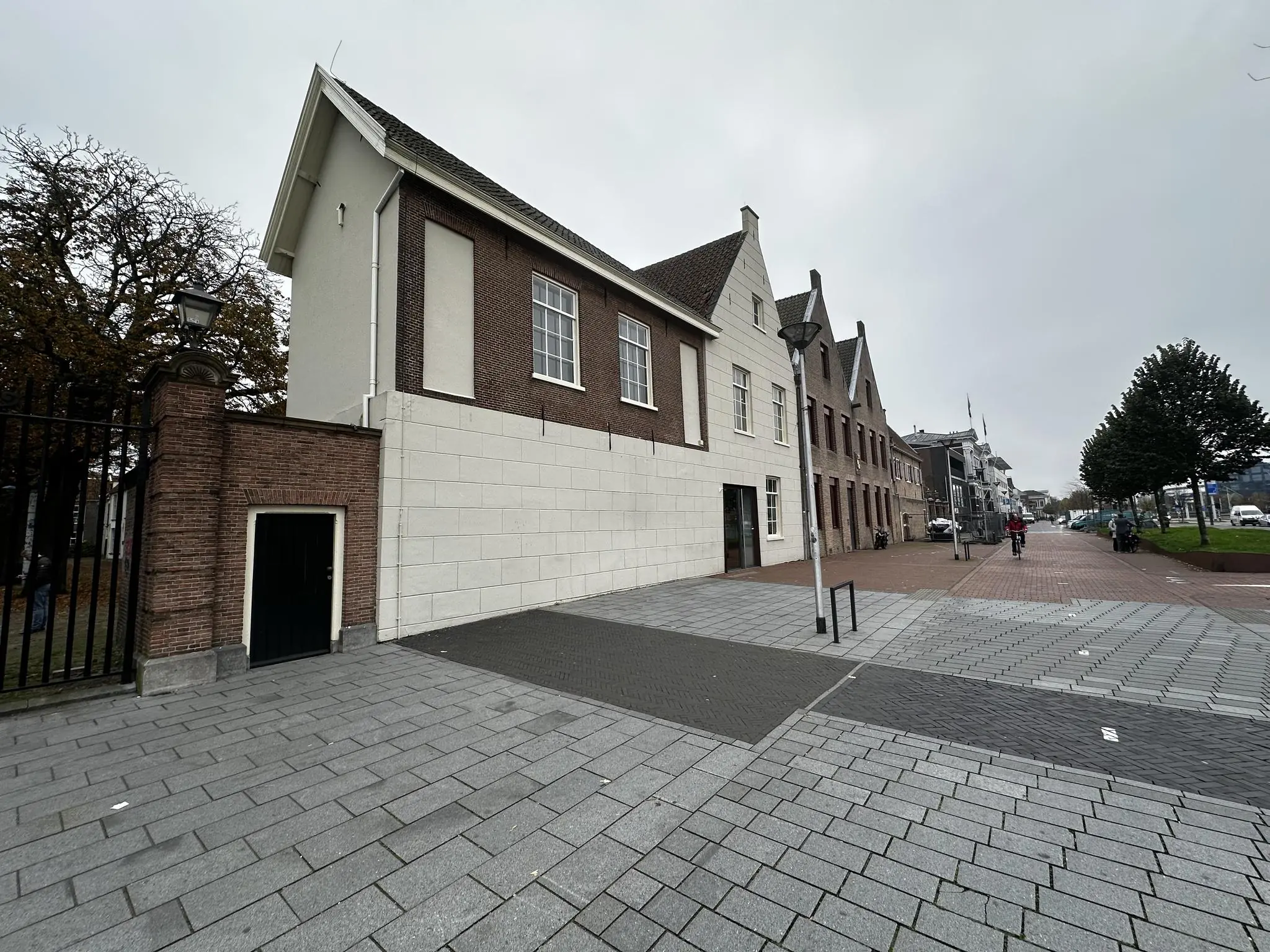 Straatbeeld van het Sint-Agathaplein met historische gebouwen en een fietser op een bewolkte dag.